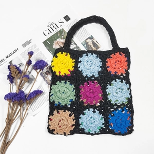 Handmade crochet tote bag with colorful granny square floral patterns on black background