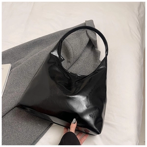 Detail shot of a black glossy hobo bag made of high-shine leather on a soft background