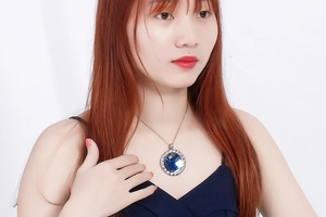 Close-up of a blue crystal pendant necklace with silver twisted chain on a model
