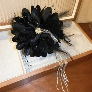 Détail de la pince à cheveux en plumes noires avec glands en strass et perles sur bois