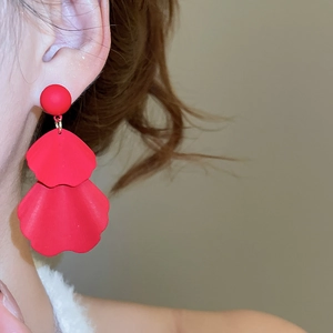 Detailed close-up of matte red flower petal drop earrings worn on a model for an elegant look