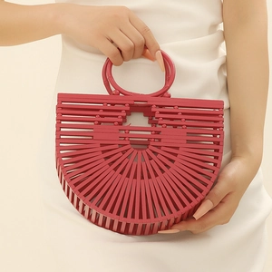 Detail of red bamboo handbag featuring a semi-circle cutout design and round handle