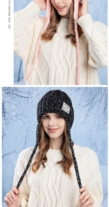 Detail of pink knitted winter beanie with ear flaps and decorative woven ties