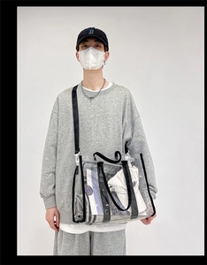 Detailed view of clear PVC shoulder bag with black strap worn by a model