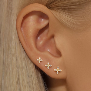 Close-up of three gold clover earrings with sparkling cubic zirconia on a model
