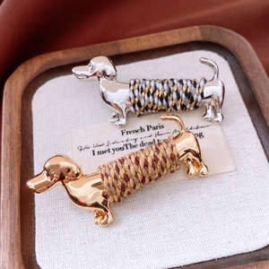 Detailed close-up of gold and silver dachshund brooches with colored thread weaving