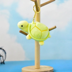 Detailed view of a cute mini green plush sea turtle keychain hanging on a wooden display tree