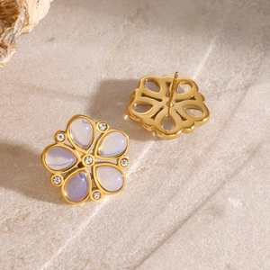 Detail of gold floral stud earrings with lilac gemstones and white crystal accents