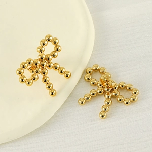 Polished 18k gold plated stainless steel beaded bow earrings on a minimalist tray