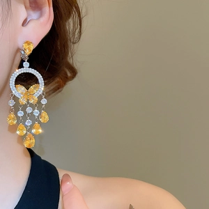 Detailed close-up of tassel earrings with yellow teardrop gems and butterfly design