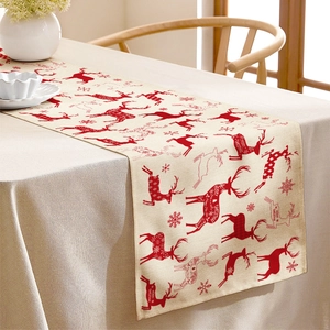 Close-up of beige linen table runner with red reindeer and snowflakes for Christmas