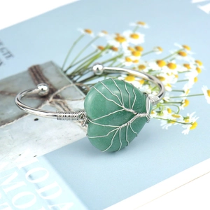 Detail of silver wire wrapped green heart crystal on a handmade open bangle bracelet