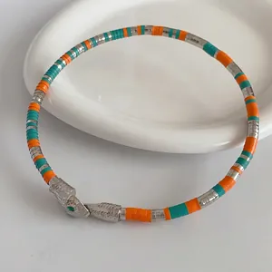 Exotic snake-shaped wrap bracelet with orange and turquoise beads on a white tray