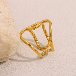Detail of 18K gold plated stainless steel knotted ring on a textured neutral background