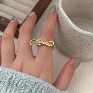 Elegant gold bow ring shown in lifestyle setting with minimalist aesthetic and metal finish
