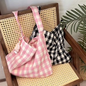 Detail of pink and black checkered canvas tote bags on a vintage wooden chair