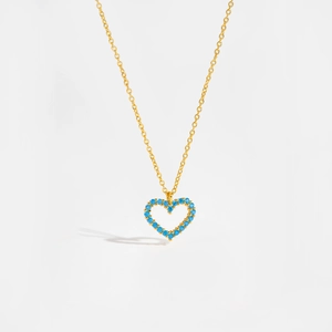 Detailed macro view of a gold-plated heart necklace with blue pavé crystals on white background