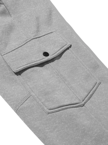 Detailed macro view of gray fleece cargo pants featuring a pocket with black metal snap button