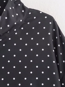 Gros plan de la veste noire à pois blancs montrant la texture fine du tissu