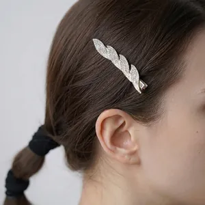 Elegant silver leaf hair clip with white rhinestones worn on hair by a model