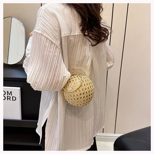 Detailed shot of spherical evening bag with golden woven texture and metal ring handle