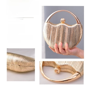 Close-up of champagne gold pleated fabric, metal handle and spherical clasp of evening bag
