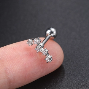 Detailed macro view of silver steel helix stud with five sparkling zircons on a fingertip
