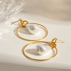 Golden stainless steel hoop earrings with baroque pearls on a minimalist background