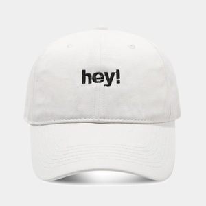 Detail of white cotton baseball cap showing black 'hey!' embroidery and stitching