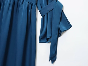 Detail of navy blue satin dress featuring elegant cuff ties and refined waist pleats