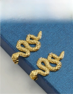Detail of 18K gold snake earrings showing scale texture and inlaid sparkling crystals