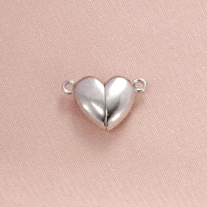 Close-up of heart-shaped magnetic clasp in silver steel on textured pink fabric
