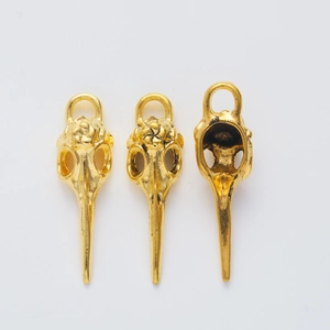 Detailed close-up of golden vintage bird skull charms with intricate metallic textures