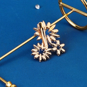 Detailed view of a golden floral metal hair clip with rhinestones on a blue textured background