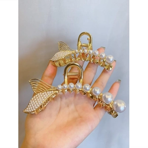 Detailed shot of gold fishtail hair claws with gradient pearls and sparkling rhinestones