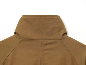 Detailed close-up of khaki twill fabric and refined stitching on a casual short trench coat