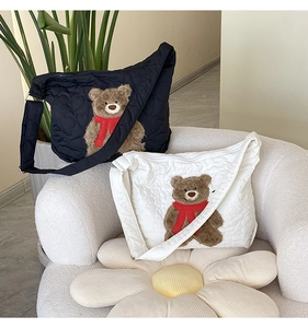 Close-up of quilted tote bags in black and white with red scarf teddy bear charms