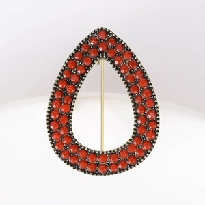 Detailed view of bohemian teardrop brooch with vintage red beads and golden pin