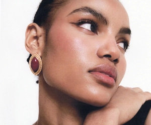 Close-up of vintage 18k gold-plated earrings with wine-red agate inlay on a model