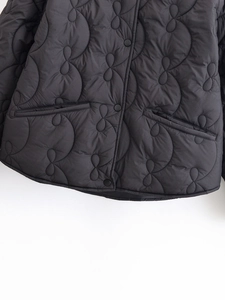 Detail of wave quilted pattern and snap buttons on women's black winter cotton jacket