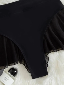 Detailed view of black bikini bottom featuring mesh panels and ruffled edge details