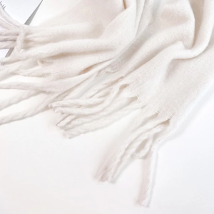 Close-up of white mohair scarf featuring soft fuzzy texture and long tassel fringe details