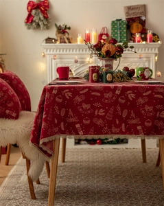 Detail of red Christmas tablecloth featuring festive bells and lace edge on wooden table