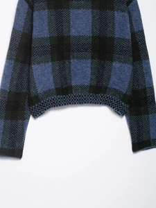 Detail of blue and black plaid knit sweater showing soft texture and ribbed hem