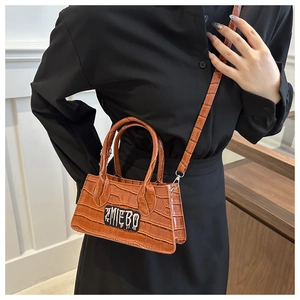 Close-up of caramel brown crocodile embossed small square bag with ZMIEBO logo on strap