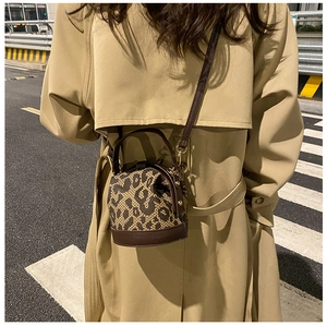 Street style shot of leopard print bucket bag with brown leather strap and khaki coat