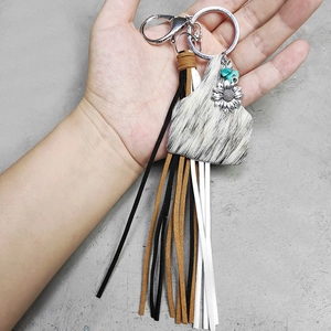 Western leather tassel keychain with bull head charm and sunflower pendant held by hand