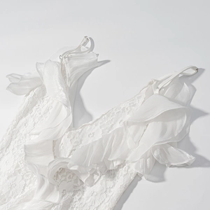 Détail de la robe en dentelle blanche montrant les fines bretelles et volants superposés