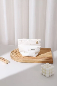 Detail of white striped makeup bag with gold flower zipper pull and embroidered heart