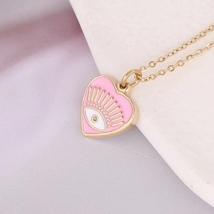 Close-up of heart-shaped gold necklace with pink enamel and evil eye detail
